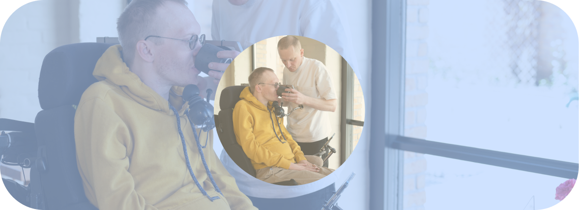 A man with a physical disability sips from a mug held by his friend. 