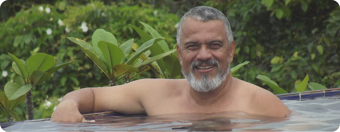 An older Australian man smiles for a photo while relaxing in a pool and enjoying activities for seniors in Melbourne.