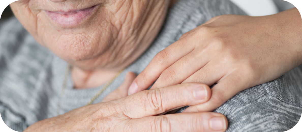A photo of a young person's hand on an older person's shoulder. Gentle reassurance can be an effective way to manage sundowning in dementia. 