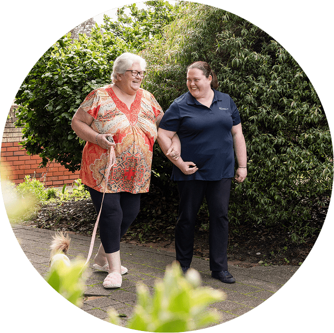 A client with The CareSide smiles with her caregiver while enjoying a walk in QLD.