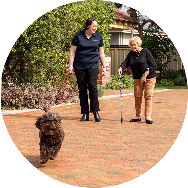A photo of an older woman receiving home care services in Rockhampton as she enjoys a walk outside with her dog and support worker from The CareSide.