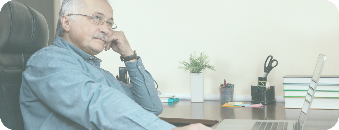 An older man sits at his computer and thinks about what to do if his home care provider shuts down.