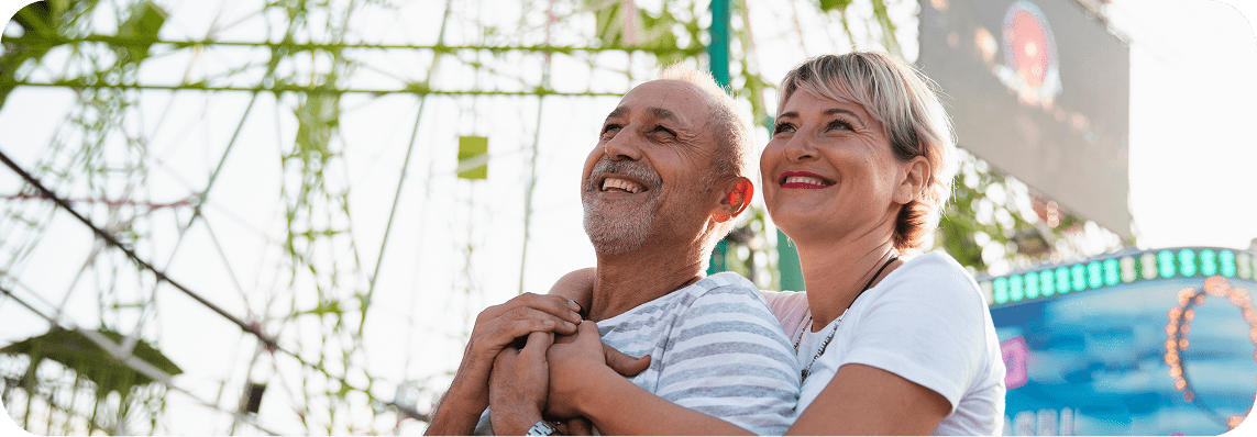 Two older people demonstrate ageing joyfully while laughing and having fun at an outdoor concert.