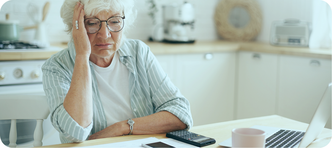 A photo of an older woman sitting at her kitchen table, reviewing her home care services forms, and considering when to transfer care.