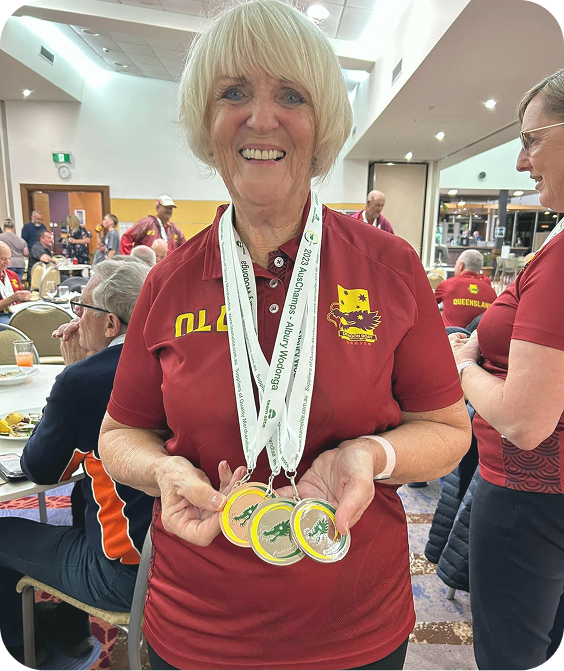 A photo of Margaret smiling and holding gold medals.